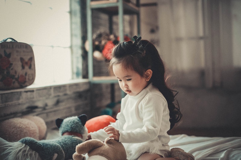 little girl on bed with toys