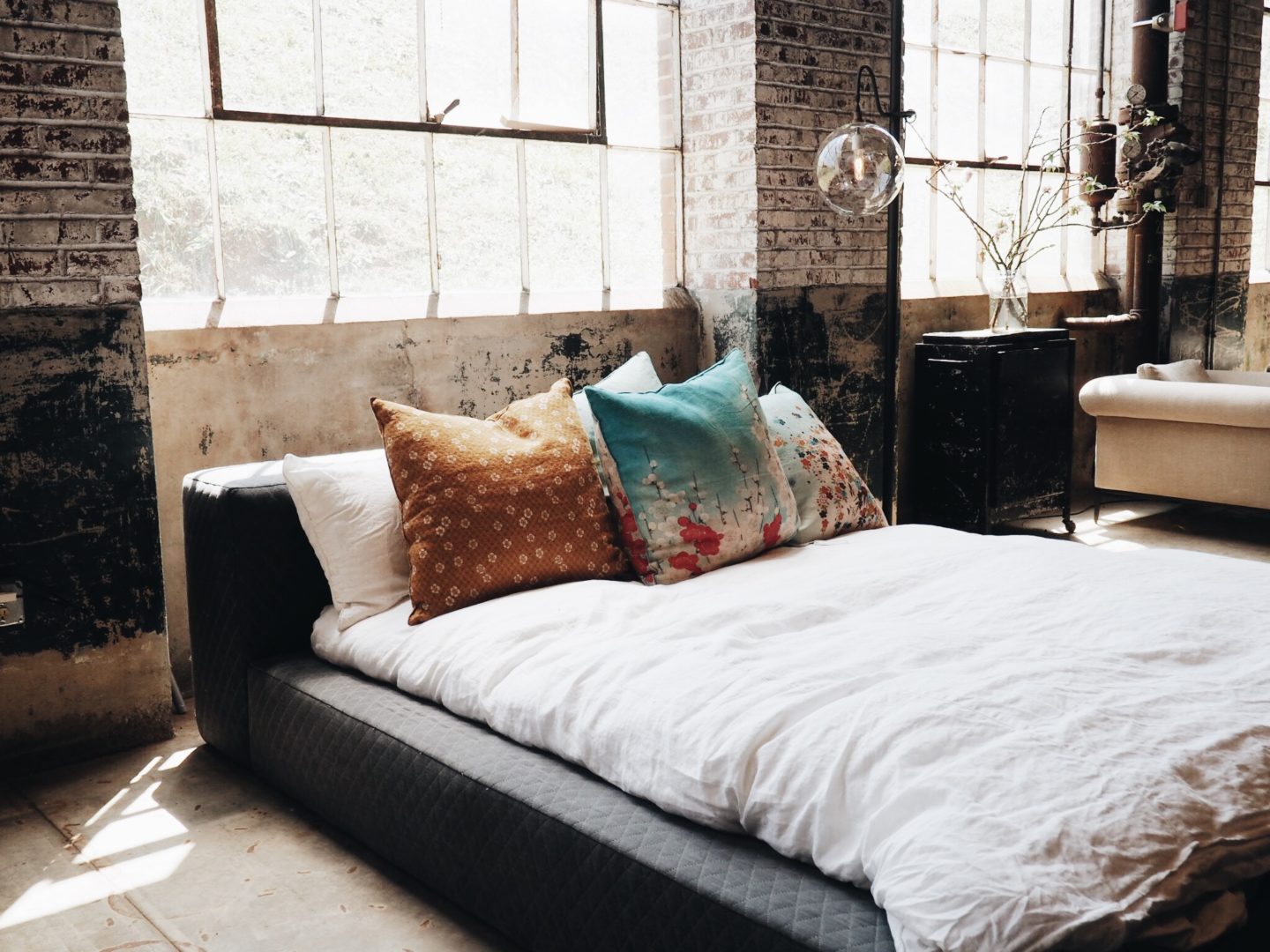 low modern bed with white sheets in a loft