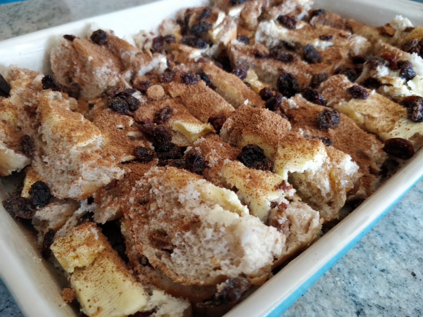 Sprinkling cinnamon onto the Hot Cross Bun and Butter Pudding