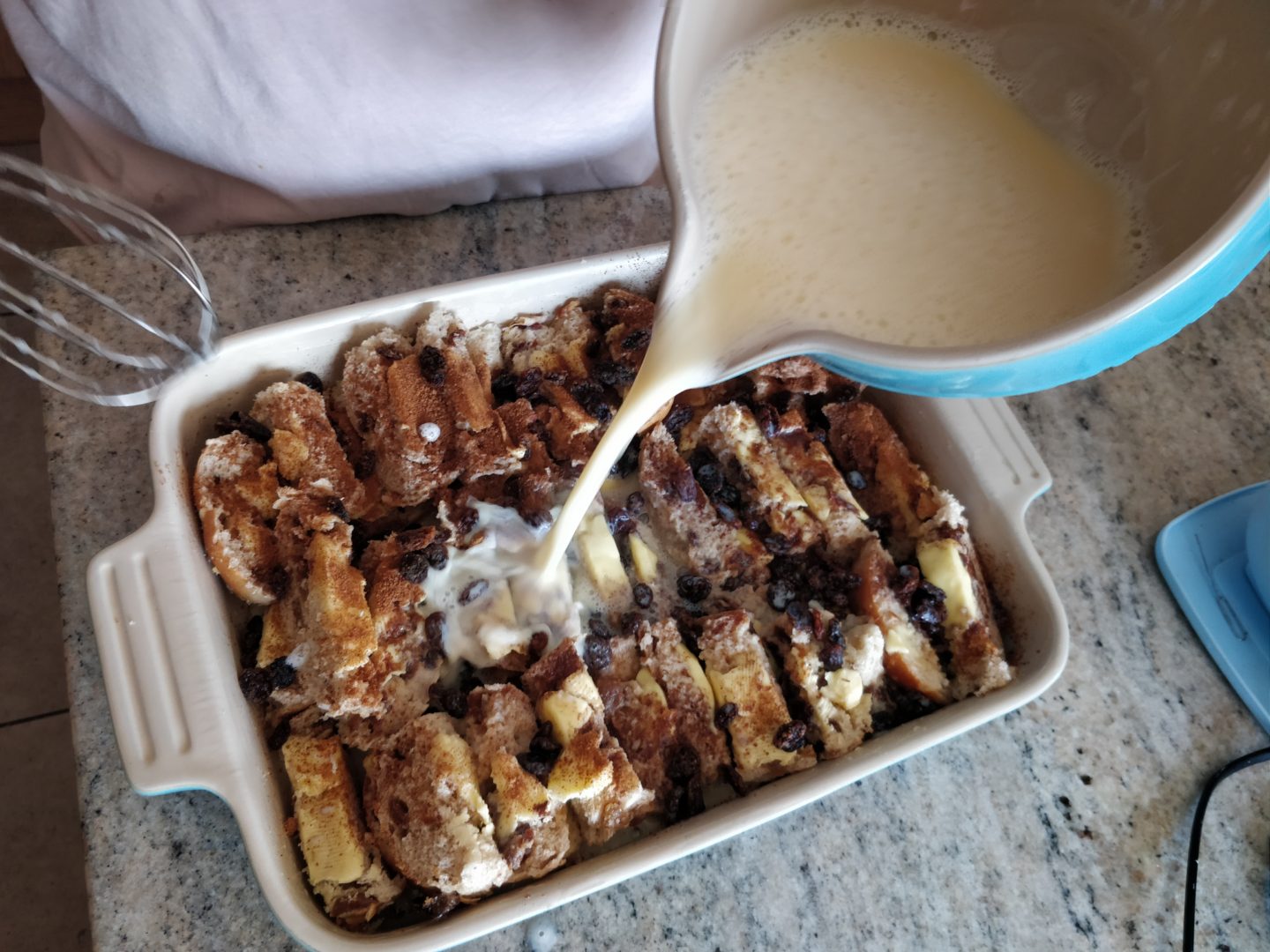 Pouring custard onto the Hot Cross Bun and Butter Pudding